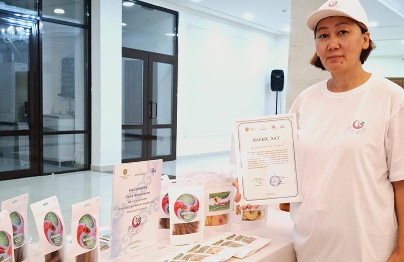 Лиза Касымова, участница проекта Qadam из Атырауской области, с продукцией собственного бизнеса и благодарственным письмом