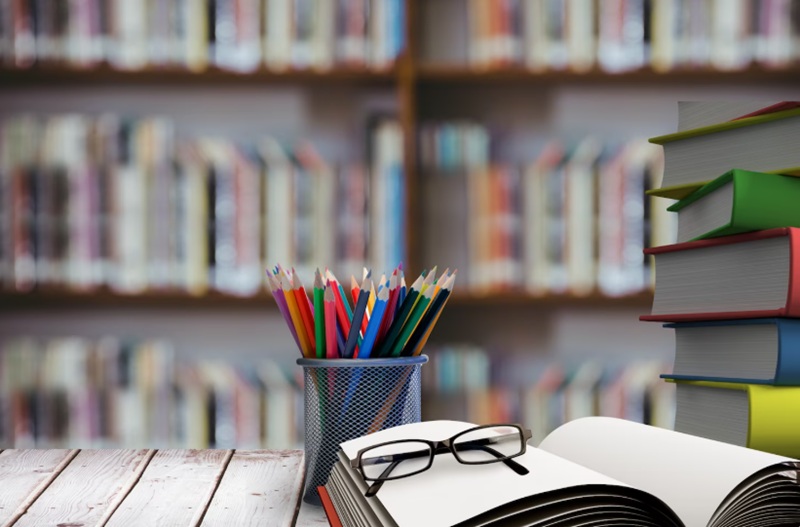 База Справедливого Казахстана ― качественное образование и воспитание патриотизма Стек книг в очках на деревянный стол - символизирующее образование в Казахстане